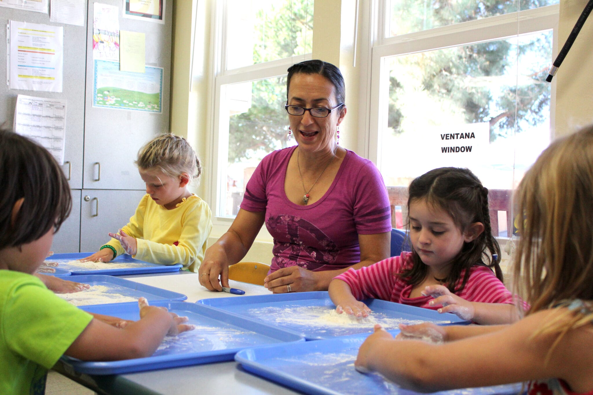 An early educator is helping children with their activity.