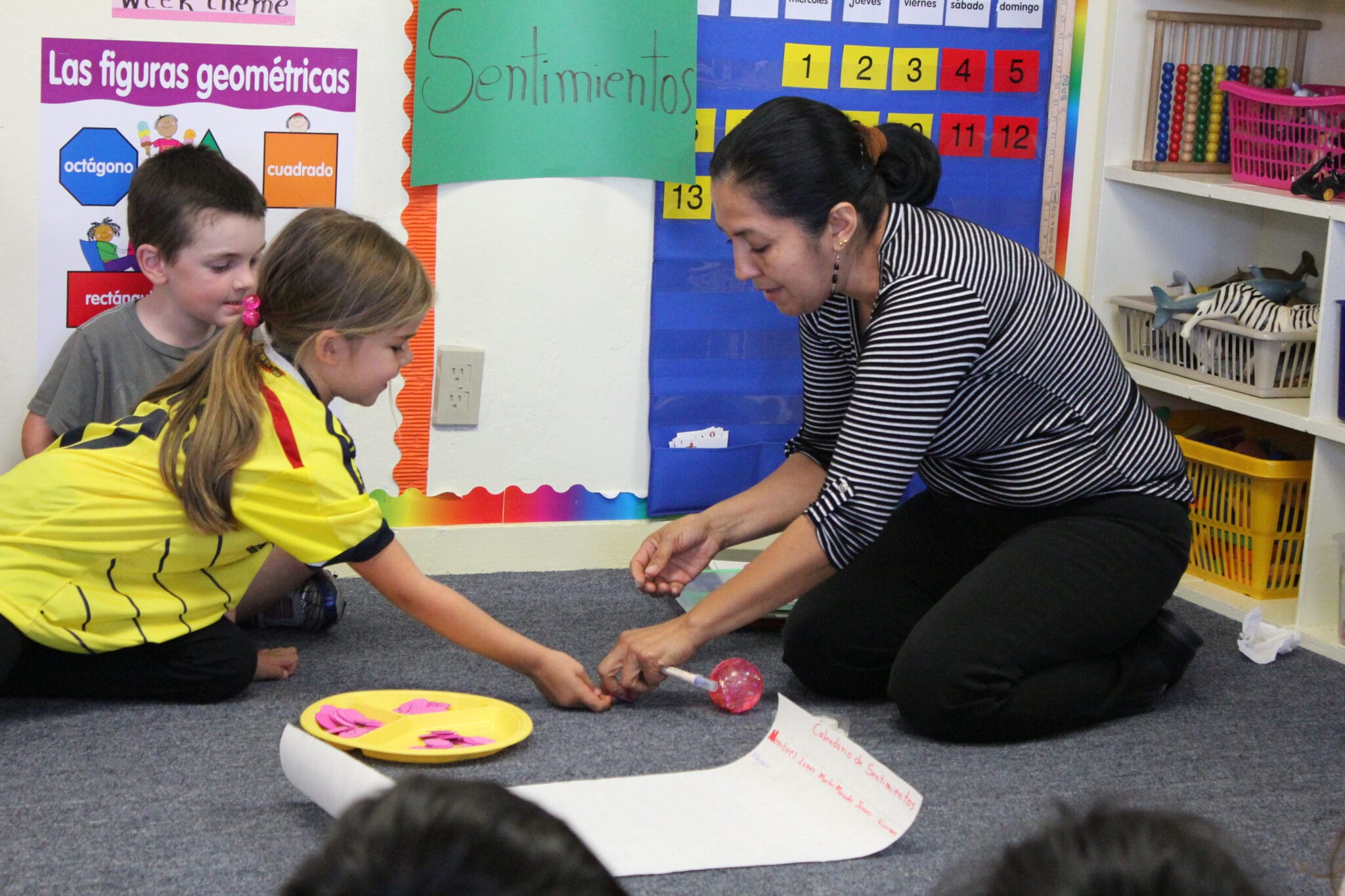 An early educator is playing a game with a student on the carpet