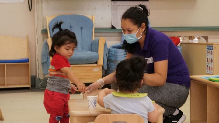 An early educator is engaging in child playtime with two children.