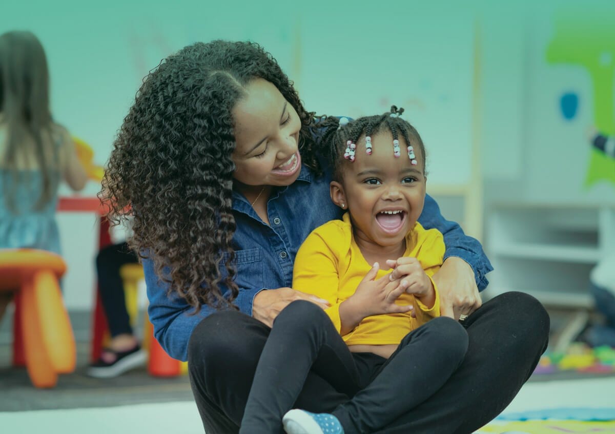 Women is laughing and playing with a child in her lap.