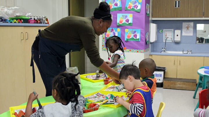 Early educator helping preschool children with an activity