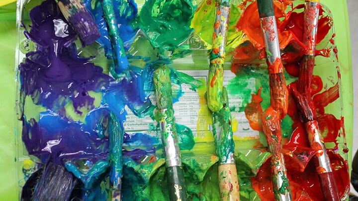 Paint brushes dipped in various paint colors.