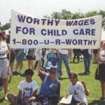 Worthy Wages rally where people are holding up a banner that says, " Worthy Wages For Child Care 1-800-U-R-WORTHY"