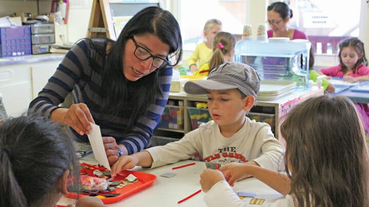 An early educator is explaining a craft activity to a child