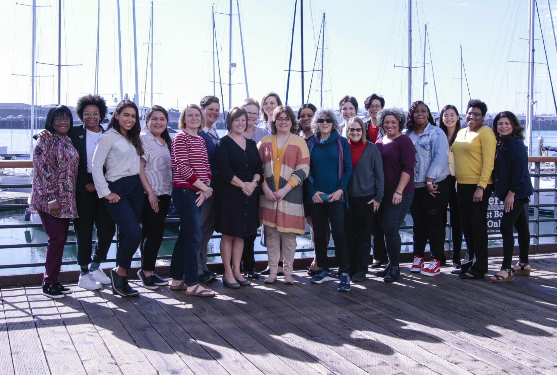 A group of women standing in front of a sailing boat dock