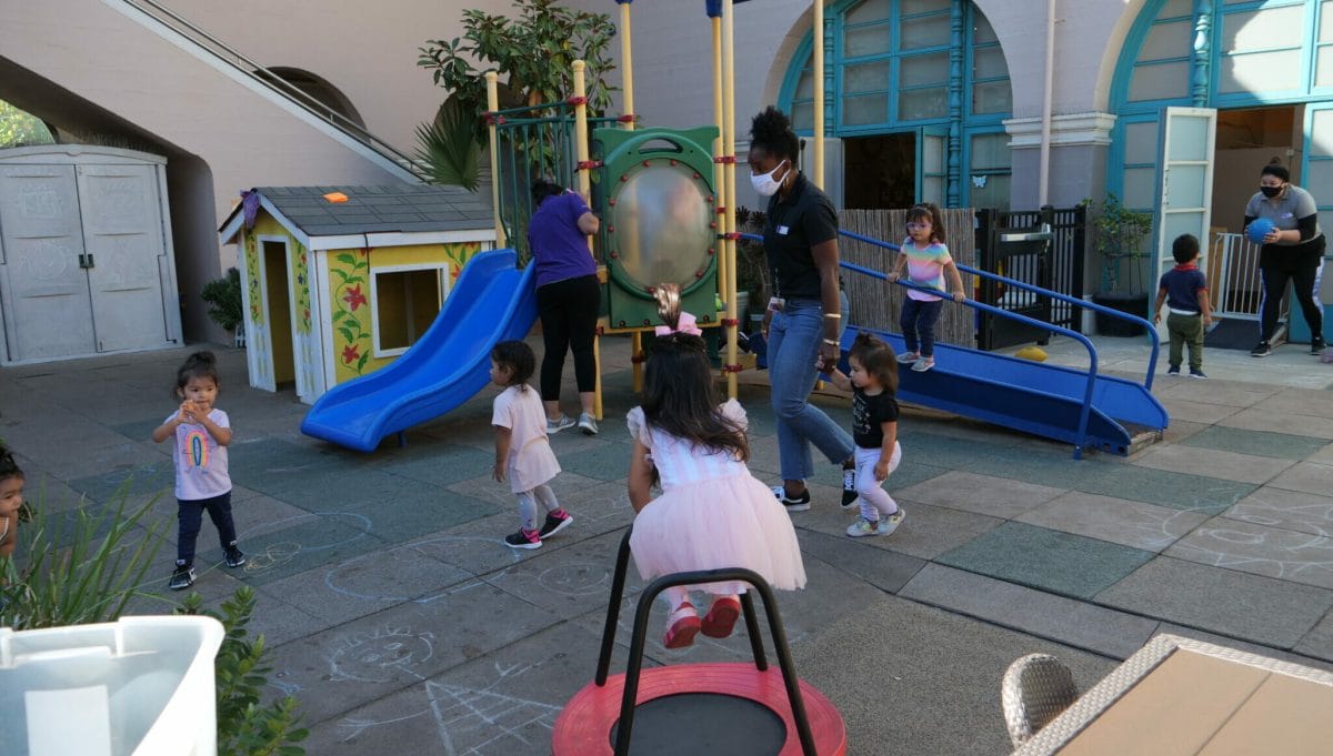 Young children and an adult educators play outside