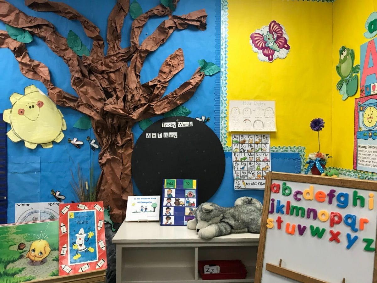 The literacy corner of an elementary school classroom, with books, paper crafts, and alphabet magnets.