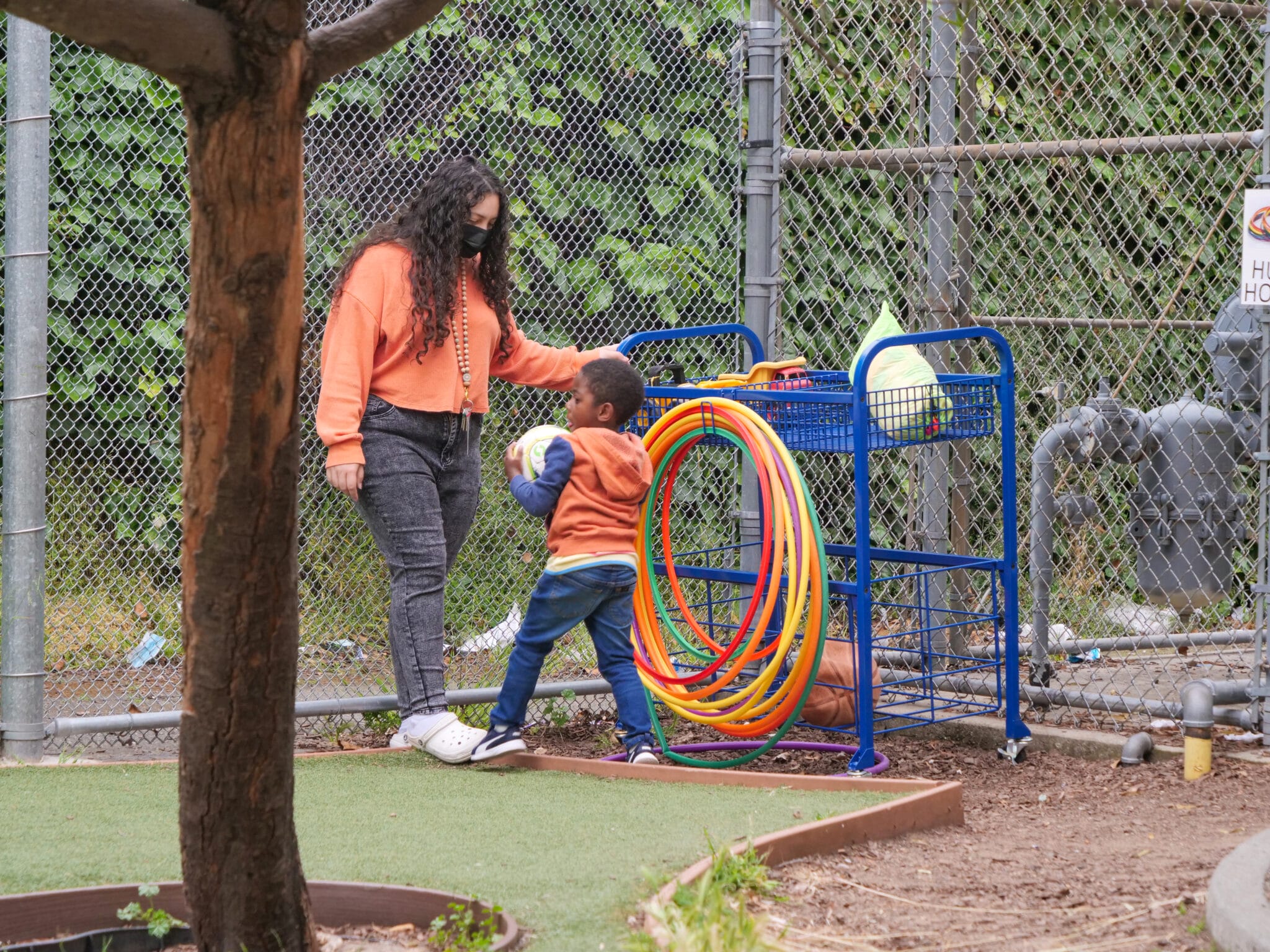 A child care worker interacts with a child as they hold on to a soccer ball.