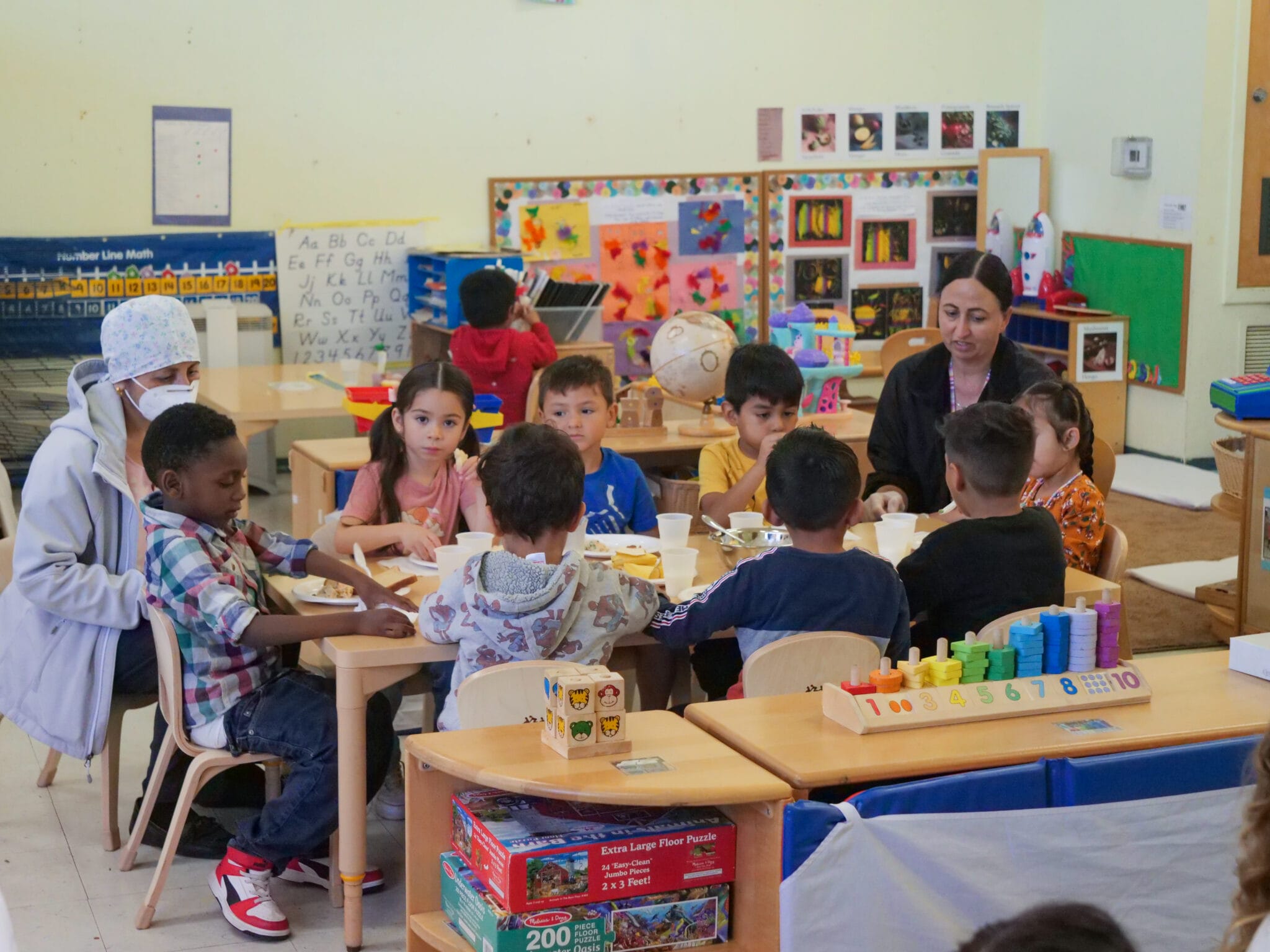 Group of children sitting together at a classroom table as they eat.