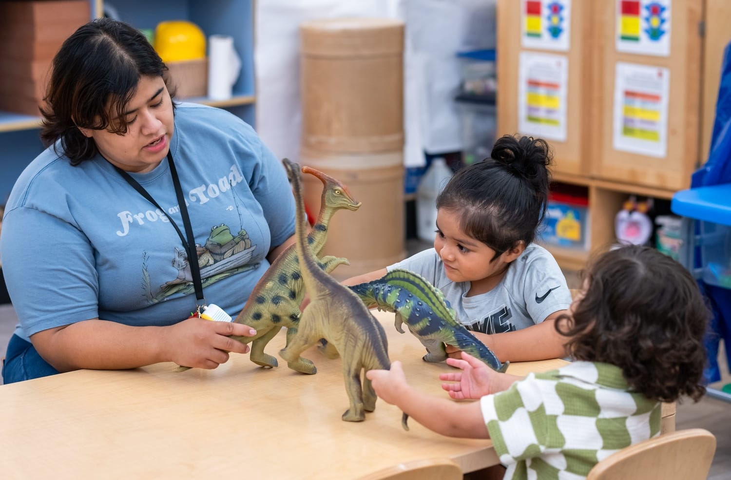 Educator and child playing with a toy dinosaur.