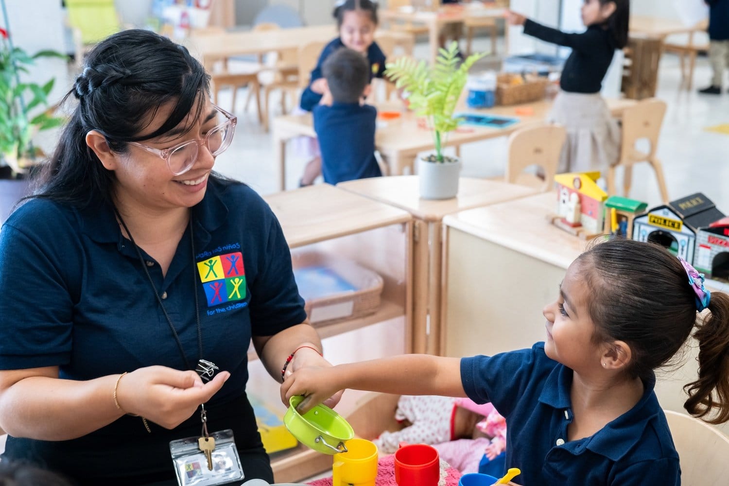A teacher and student play with a toy kitchen set.