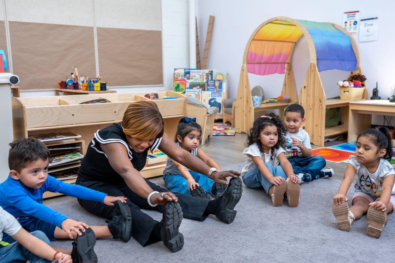 A teacher and students do stretches in the classroom.