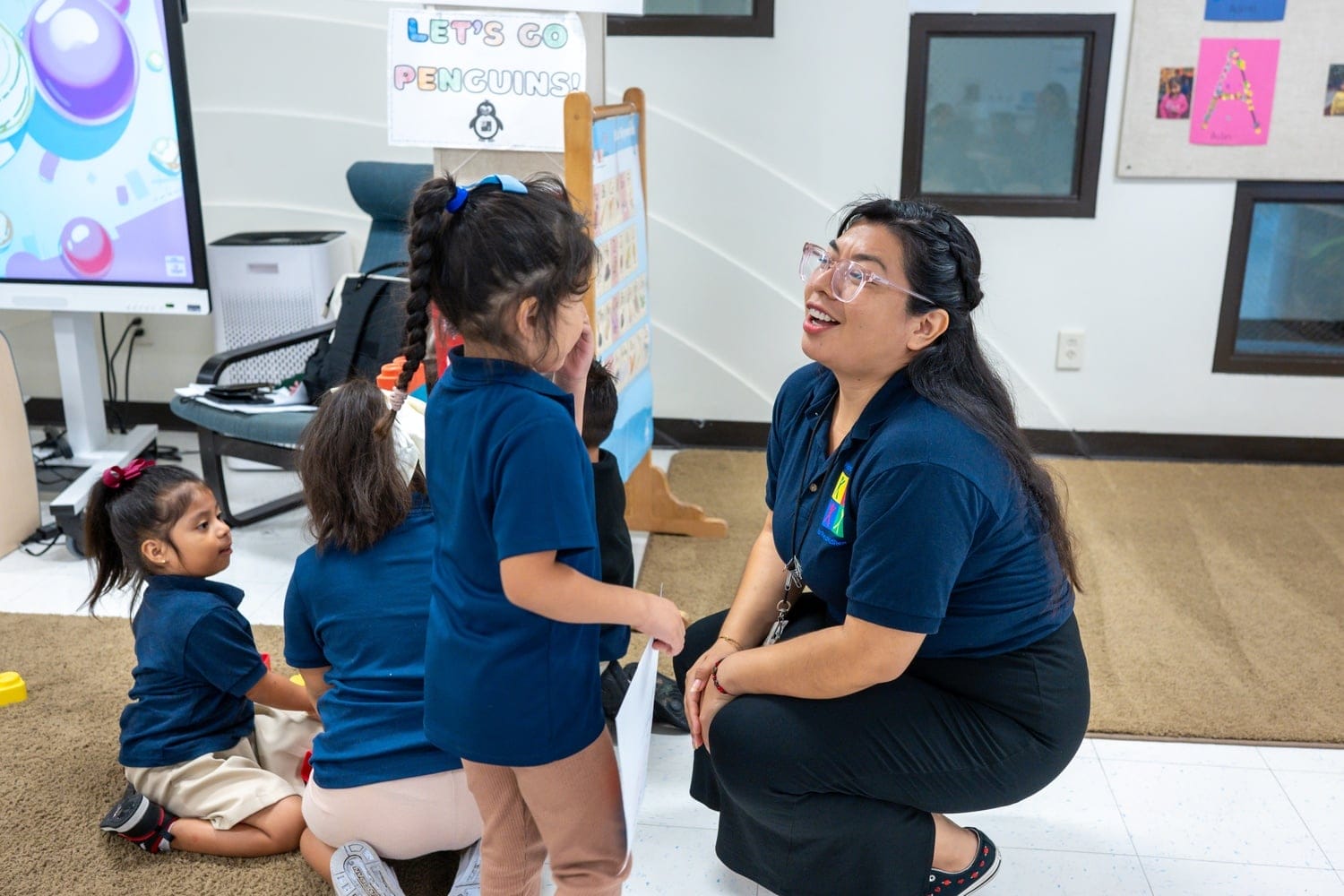 A teacher kneeling down while speaking with students.